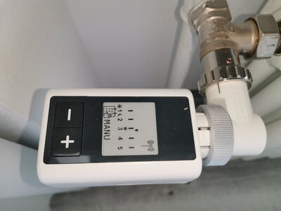 Heizkörperthermostat mit digitaler Anzeige und Plus- und Minus-Tasten an einem Heizungsrohr